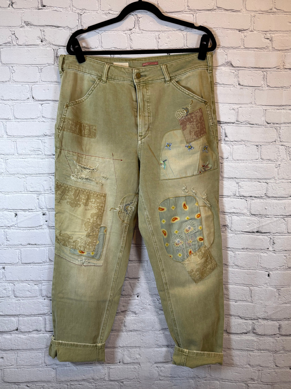 olive jeans with patches on a white brick wall background