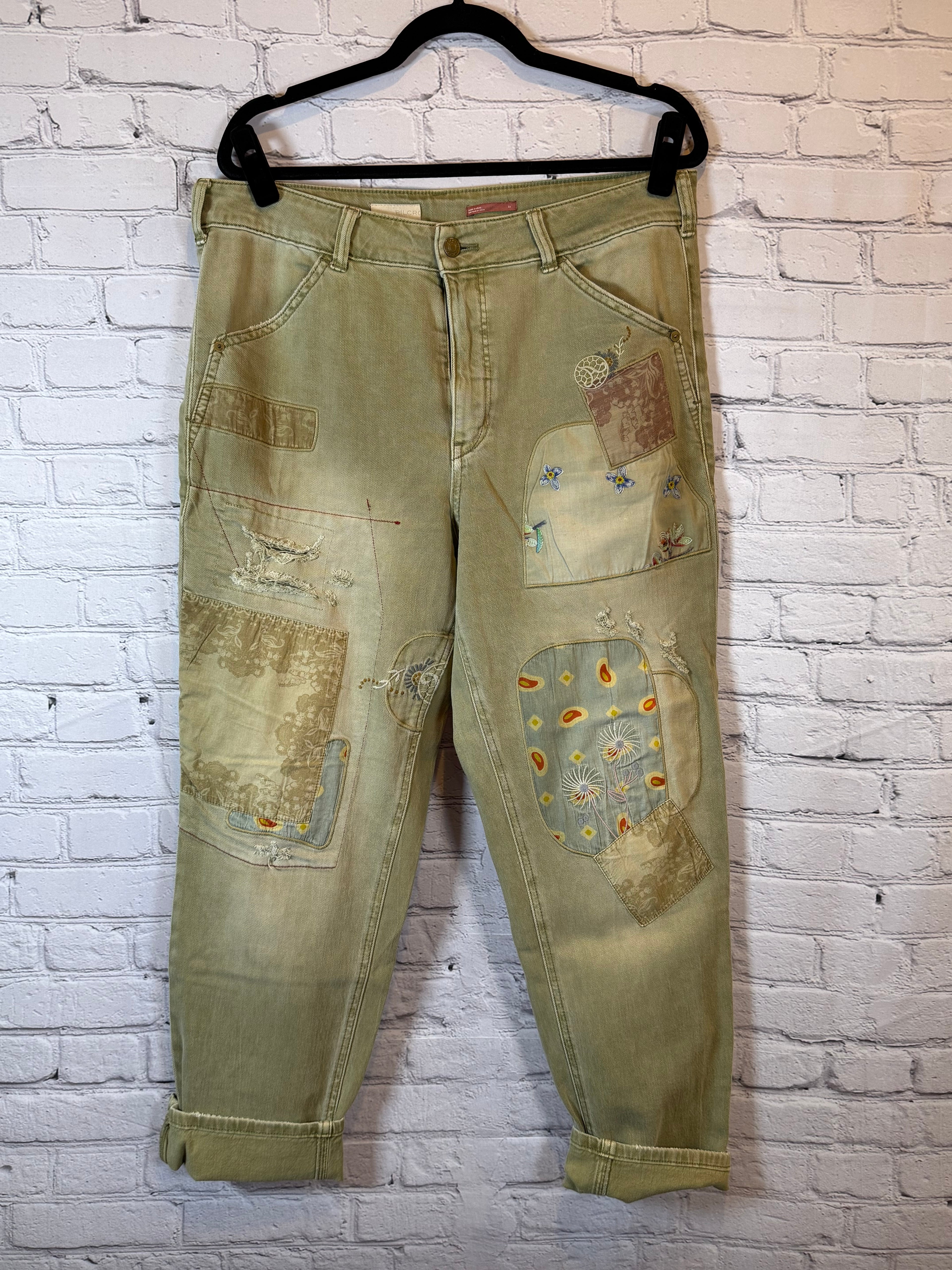 olive jeans with patches on a white brick wall background