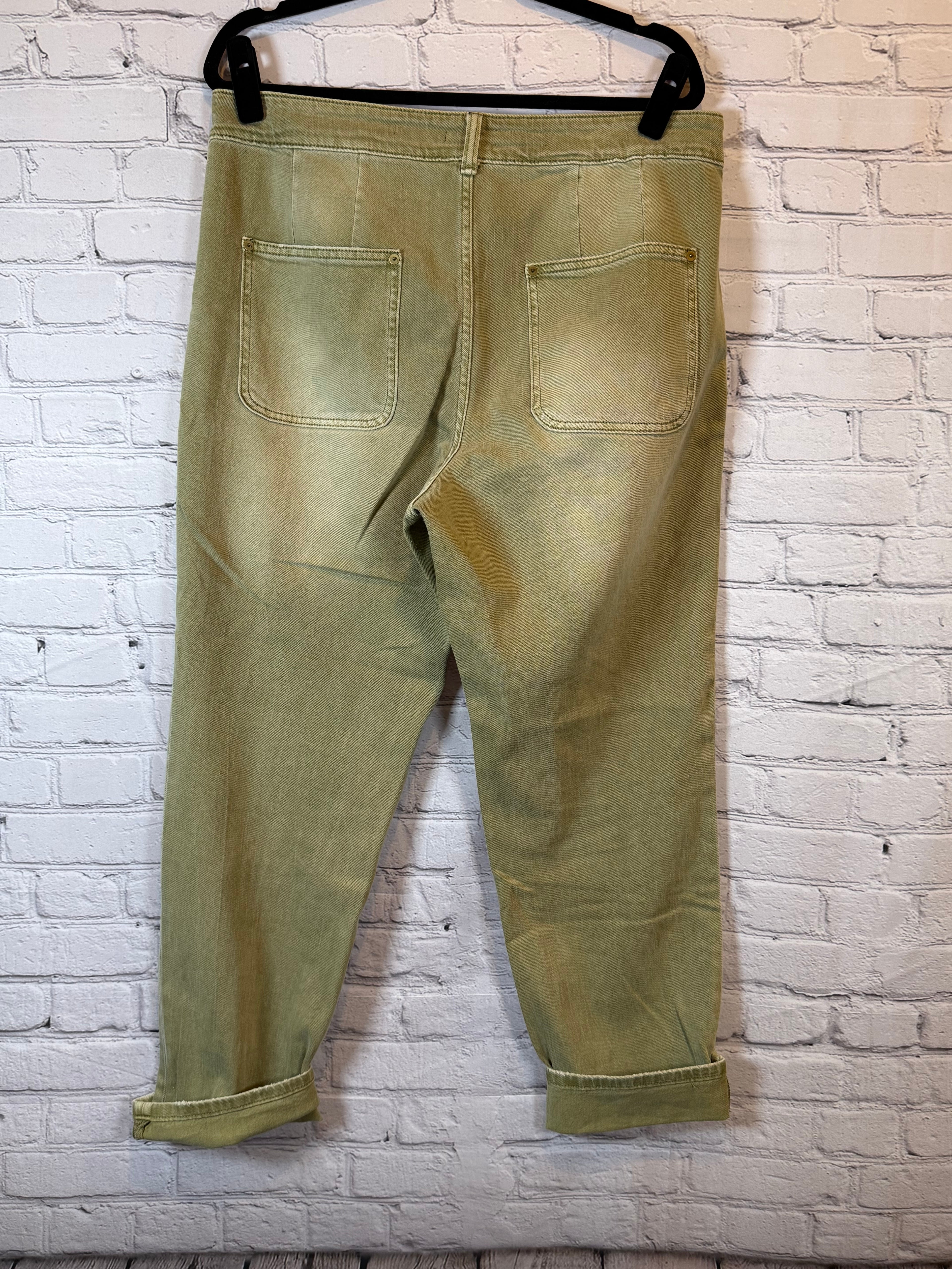 back pocket view of olive pants on a white brick wall background