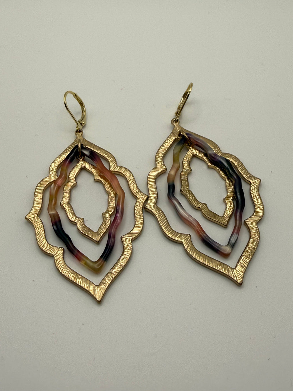 layered gold and black/tan acrylic earrings in an organic diamond shape