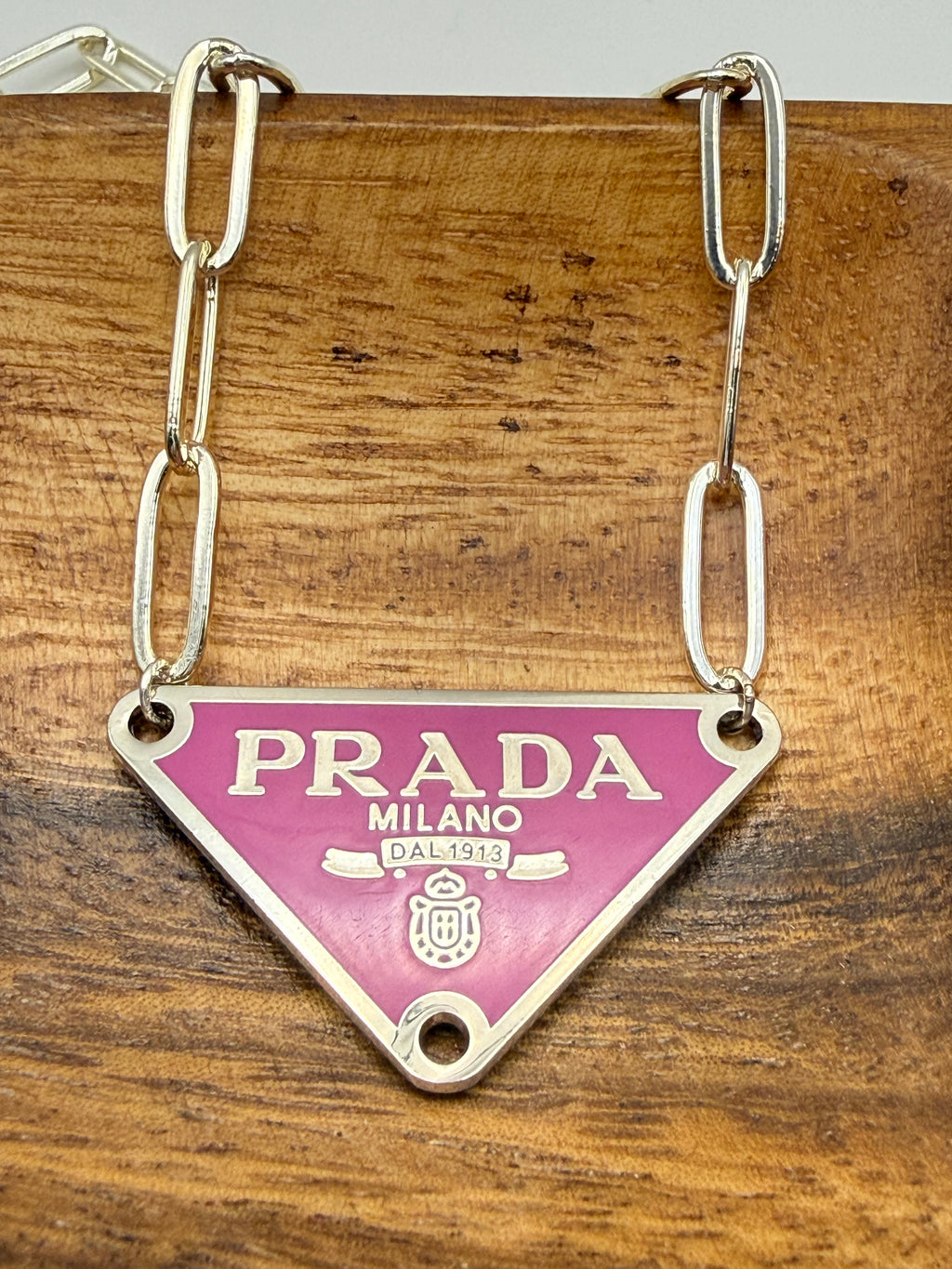 Prada necklace with pink tag on a wooden surface