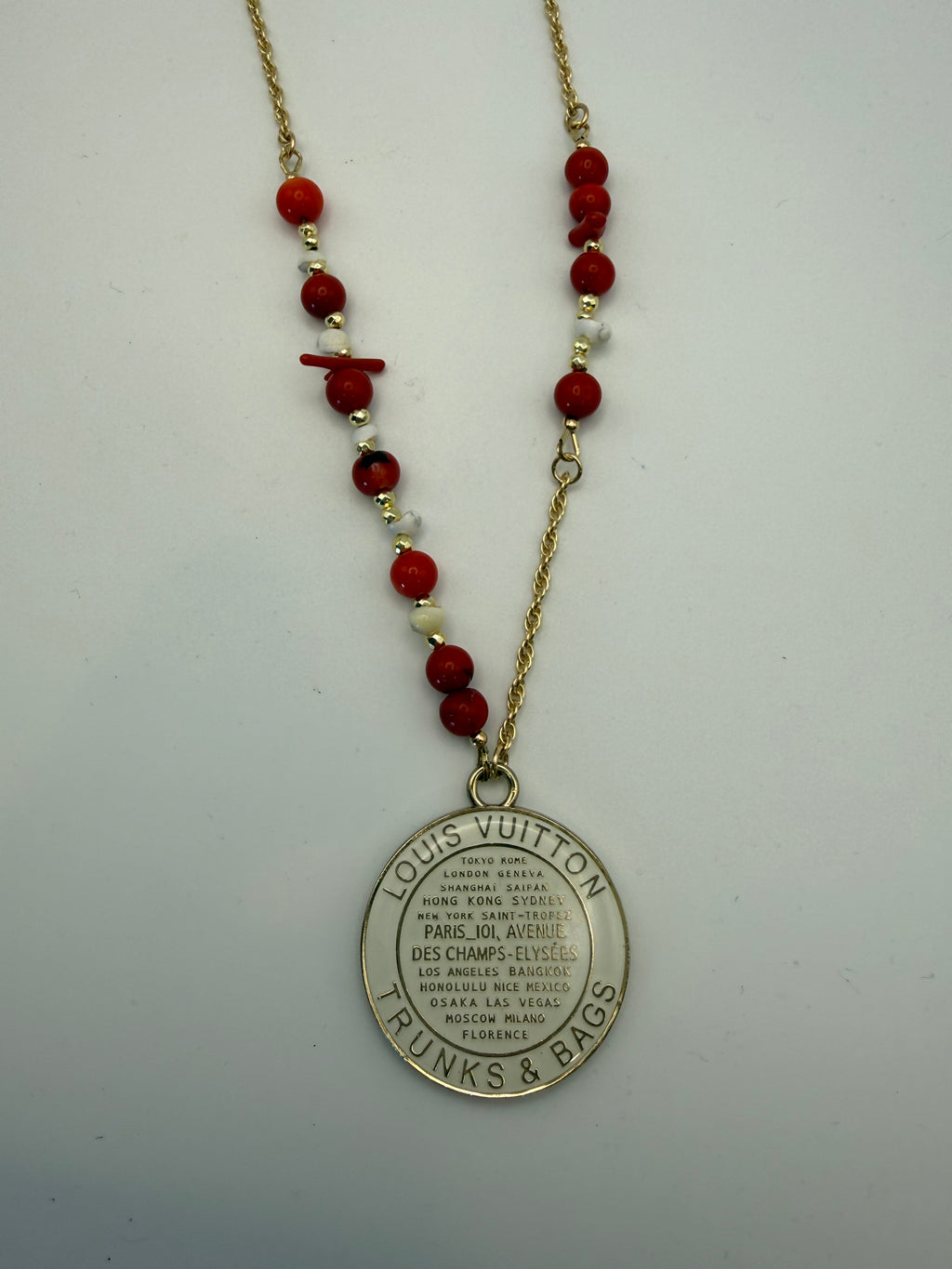 Necklace with red beads and a silver tag on a white background