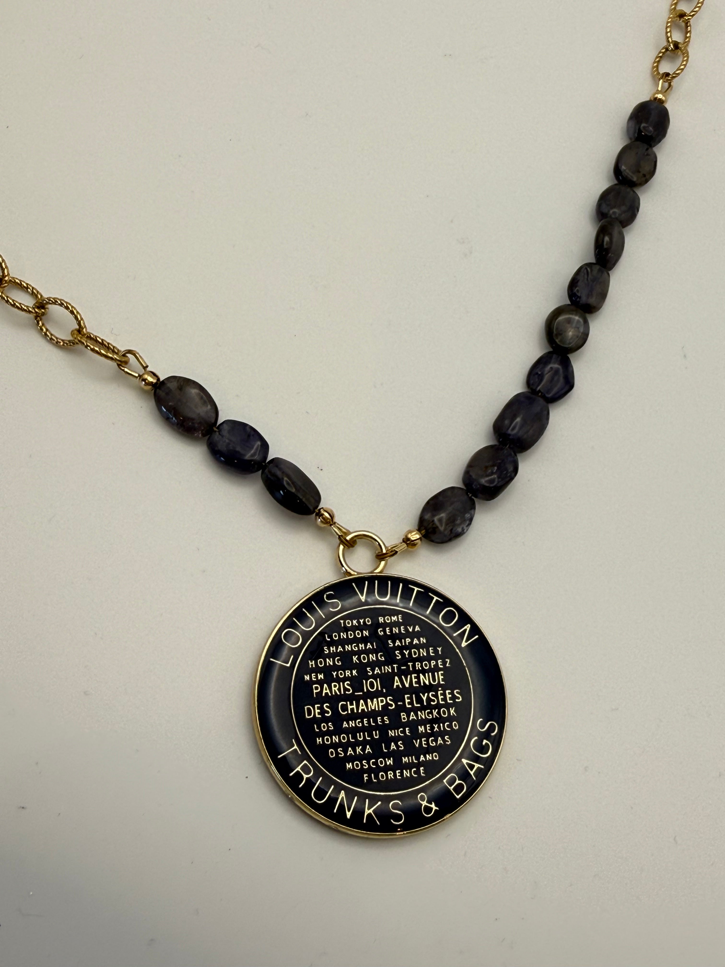 Necklace with dark bead chain and decorative pendant on a light background