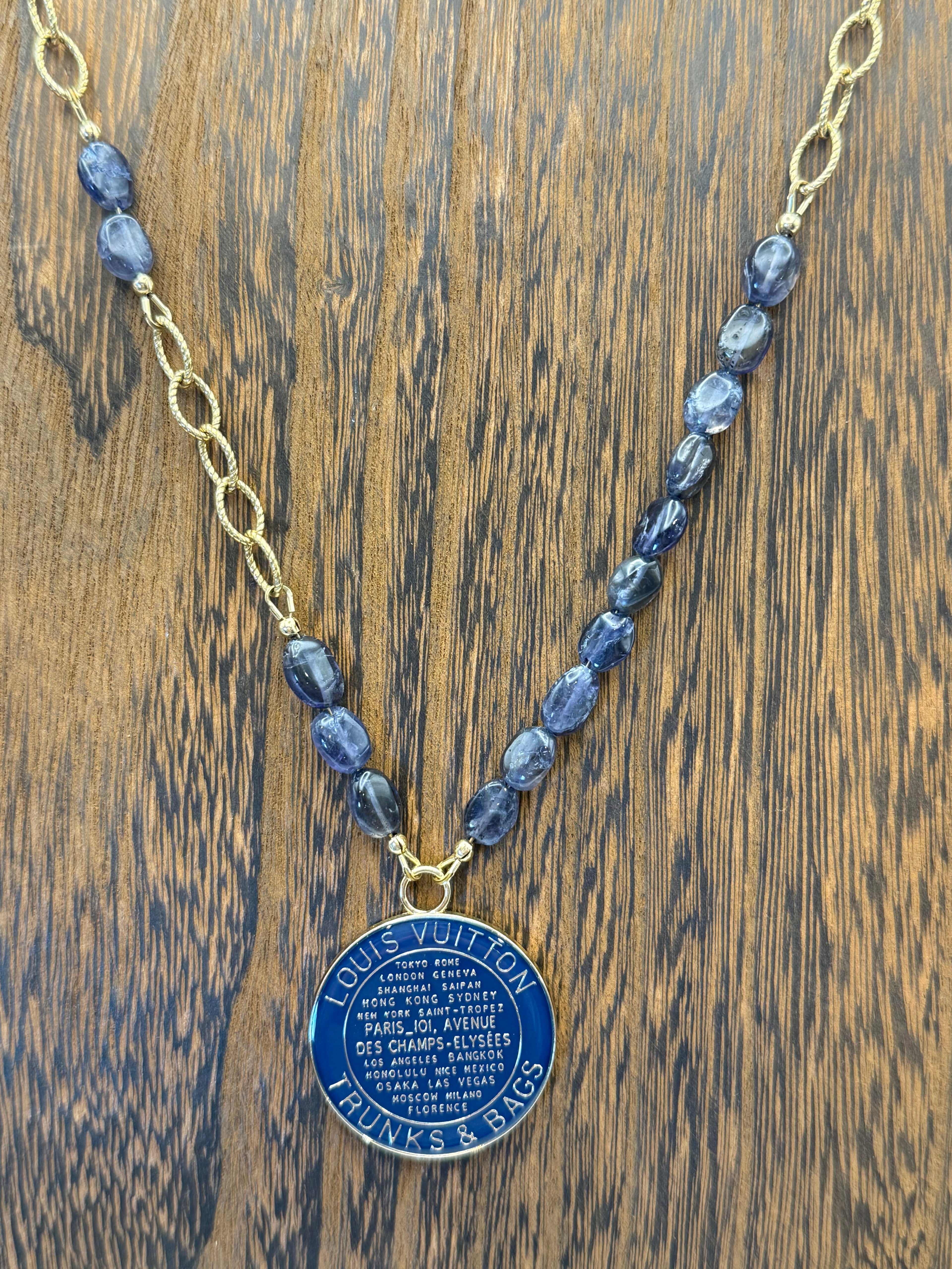 Necklace with blue pendant and gold chain on a wooden surface