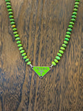 Green beaded necklace with Prada triangle logo on a wooden surface