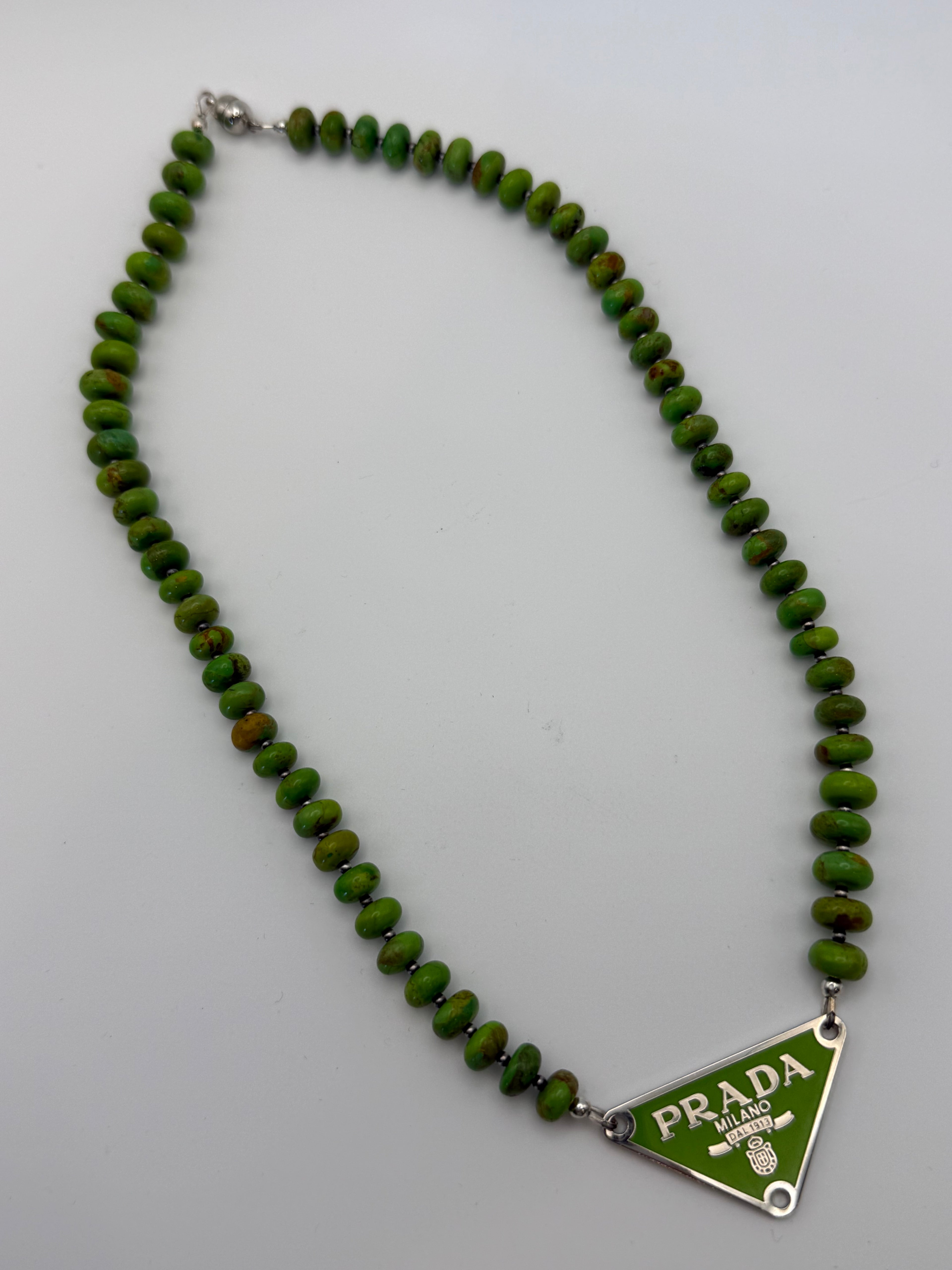 Green beaded necklace with Prada clasp on a white background