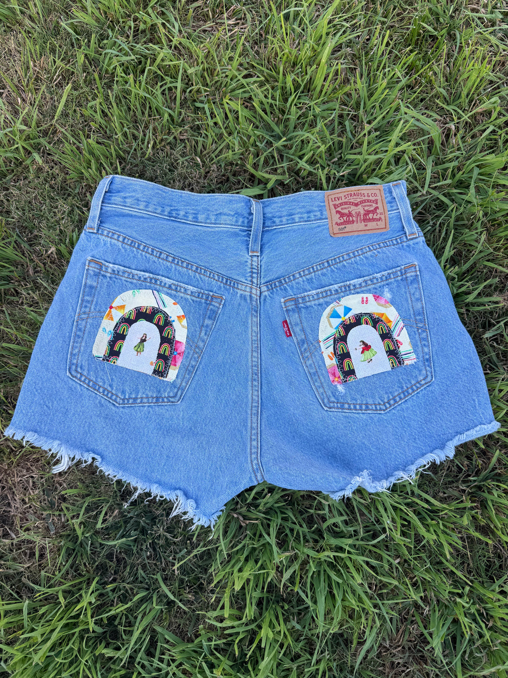 Blue denim shorts with rainbow designs on a grassy background
