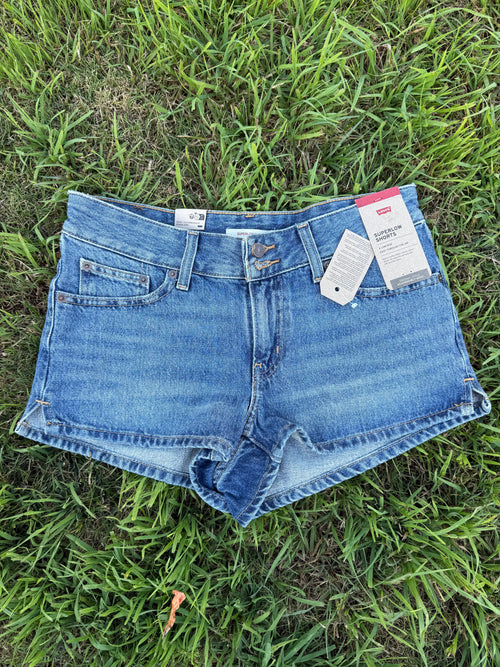 Blue denim shorts with tags on a grassy background