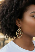 layered gold and black/tan acrylic earrings in an organic diamond shape on a model