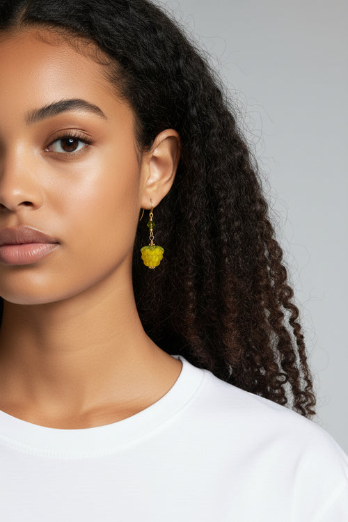 Woman wearing a yellow lamp glass berry earring against a neutral background