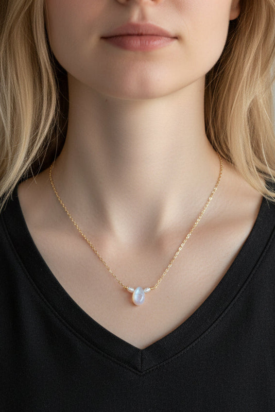 Person wearing a gold necklace with a heart-shaped pendant against a neutral background
