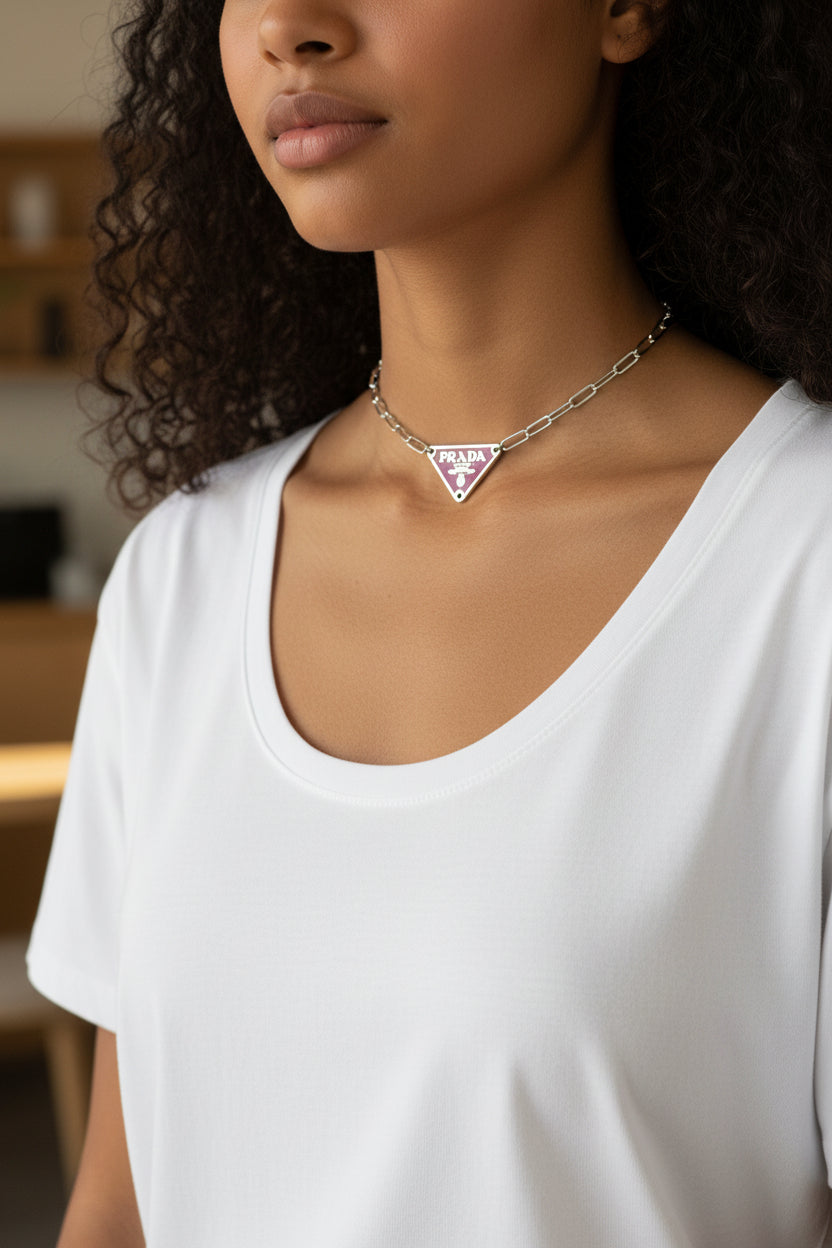 Person wearing a white shirt and a necklace with a pink prada pendant.